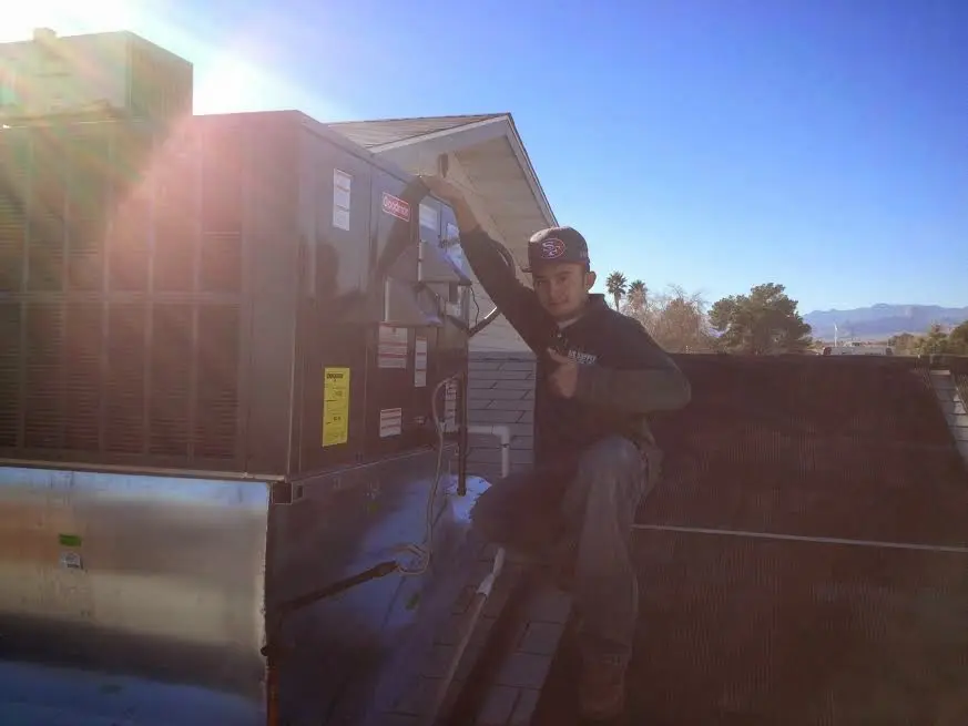 HVAC technician performing AC Tune-Up on a rooftop unit in Hudson